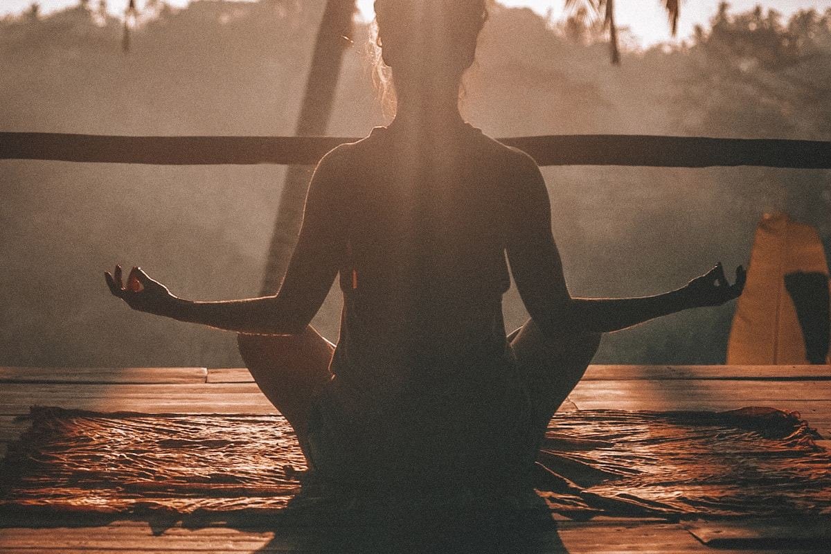 Persona meditando a contraluz al amanecer