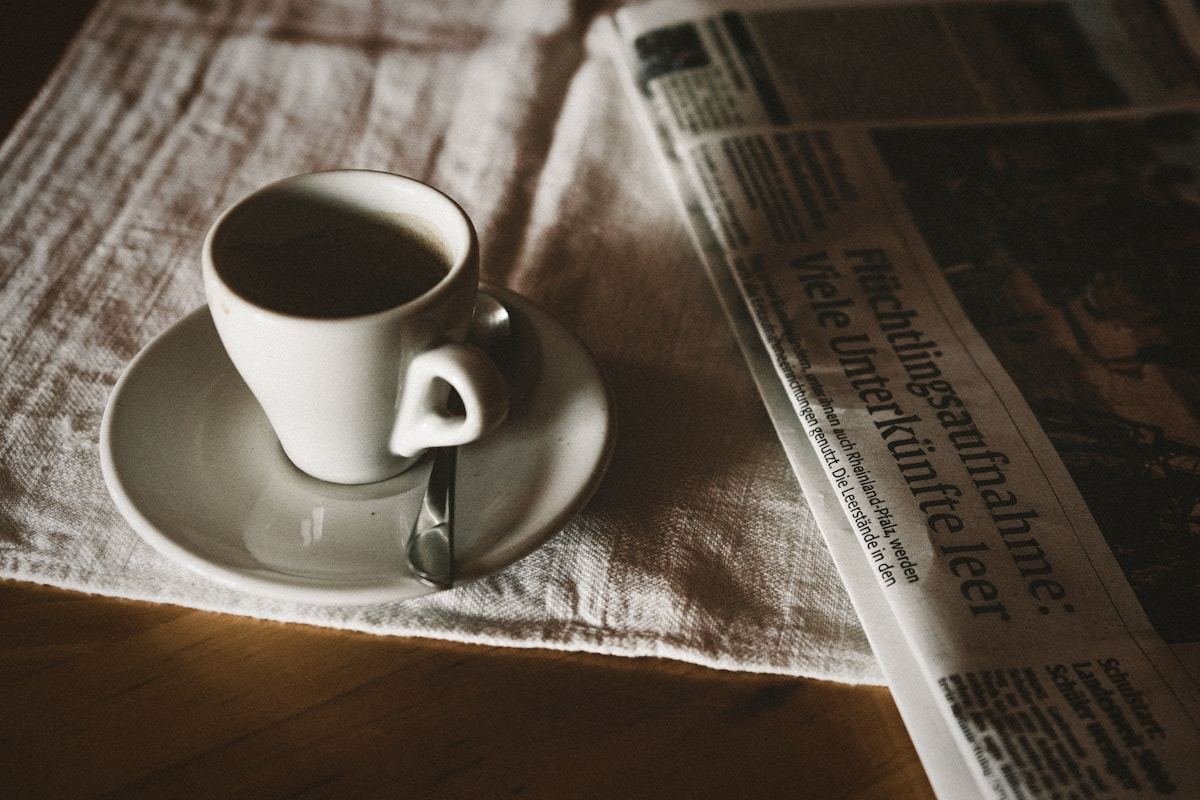 Taza de café sobre un periódico iluminado por el sol
