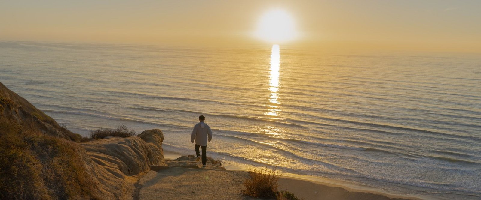 Persona caminando hacia el horizonte al atardecer